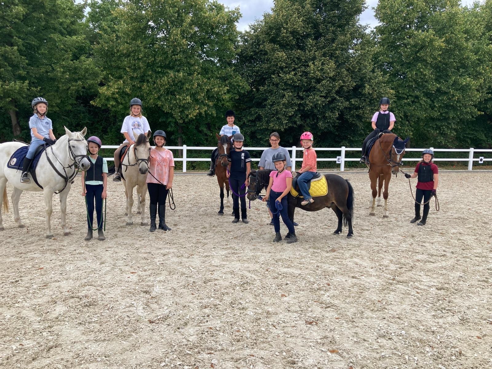 Kindergruppe auf Schulpferden und Ponys auf dem Außenreitplatz