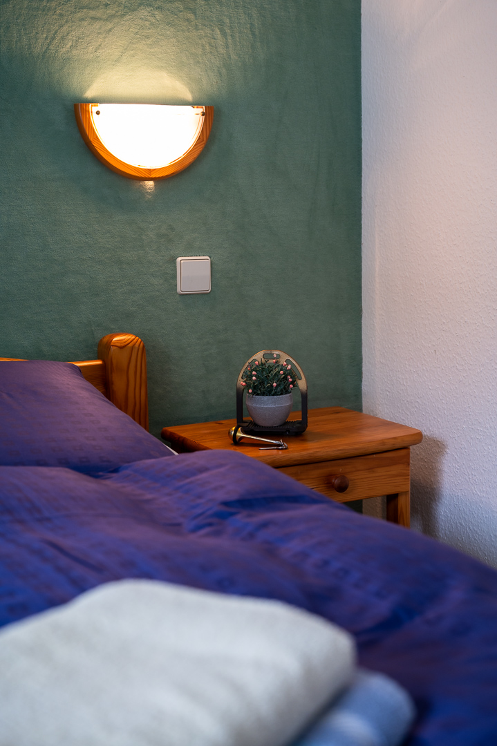 Gästezimmer mit Holzbett und warmer Wandleuchte